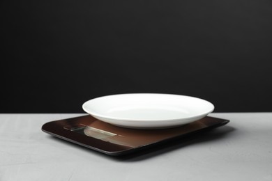 Photo of Electronic kitchen scale with plate on grey textured table against black background