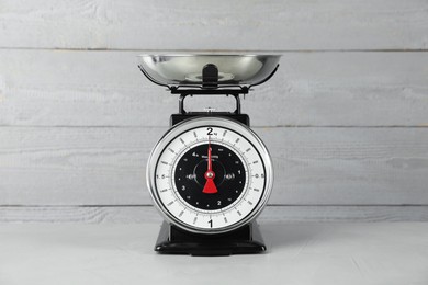 Photo of Mechanical kitchen scale with bowl on grey textured table against wooden background