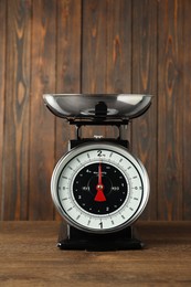 Photo of Mechanical kitchen scale with bowl on wooden table