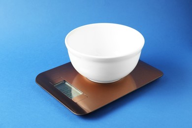 Photo of Electronic kitchen scale with empty bowl on blue background, closeup