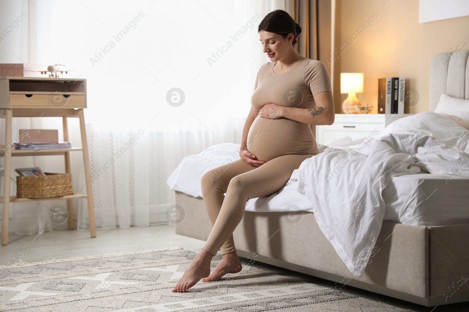 Photo of Beautiful pregnant woman on bed at home. Space for text