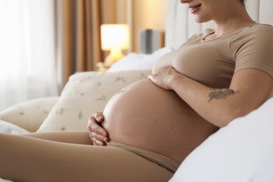 Beautiful pregnant woman on bed at home, closeup. Space for text