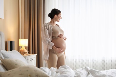 Photo of Beautiful pregnant woman near window at home