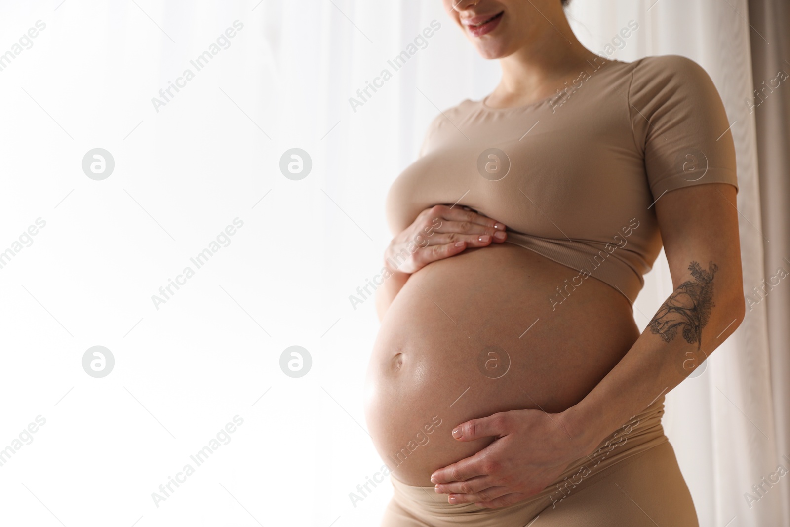 Photo of Pregnant woman near window at home, closeup. Space for text