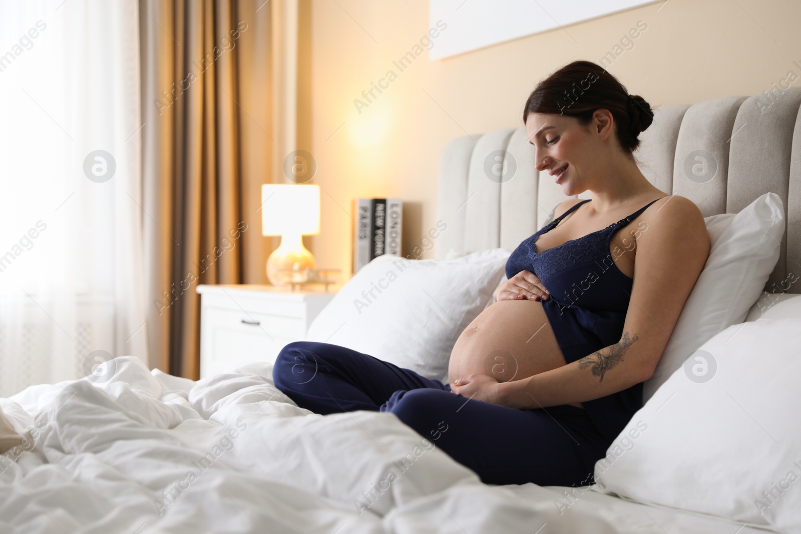 Photo of Beautiful pregnant woman on bed at home. Space for text