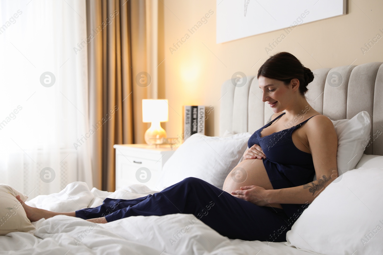 Photo of Beautiful pregnant woman on bed at home. Space for text