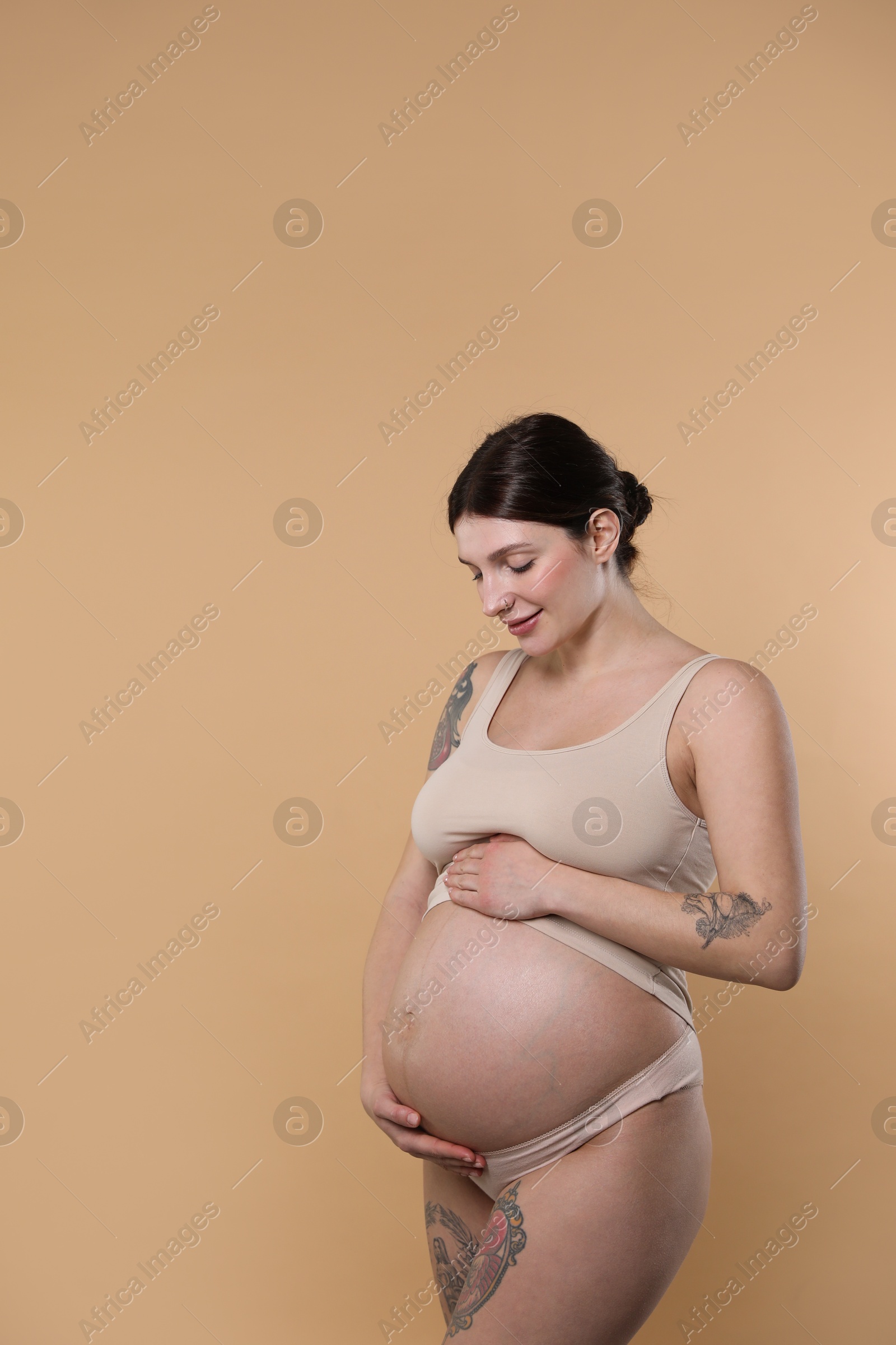 Photo of Beautiful pregnant woman with cute belly on beige background