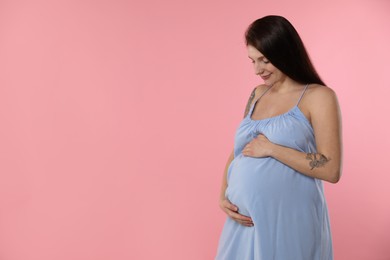 Photo of Beautiful pregnant woman with cute belly on pink background. Space for text