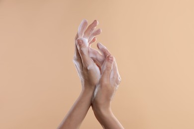 Photo of Woman washing hands with foaming soap on beige background, closeup. Hygiene