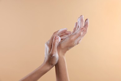 Photo of Woman washing hands with foaming soap on beige background, closeup. Hygiene