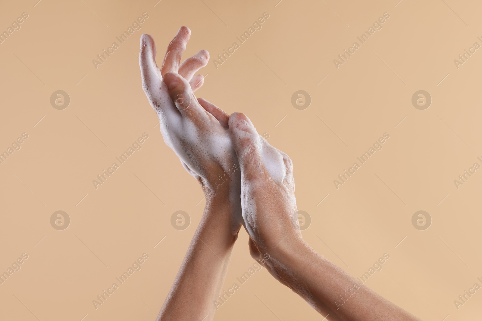 Photo of Woman washing hands with foaming soap on beige background, closeup. Hygiene