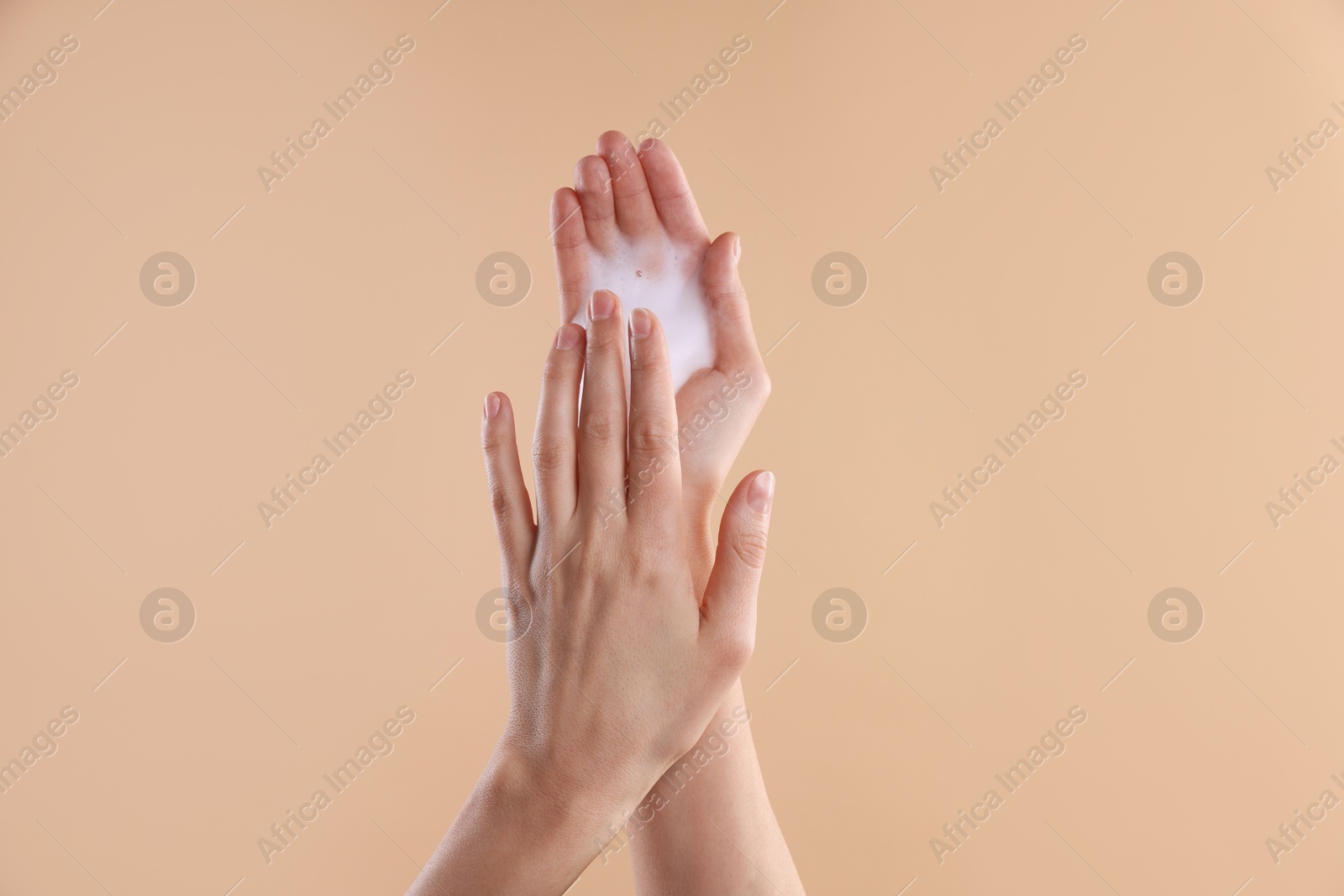 Photo of Woman washing hands with foaming soap on beige background, closeup. Hygiene