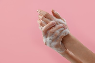 Photo of Woman washing hands with foaming soap on pink background, closeup with space for text. Hygiene