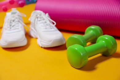 Photo of Different gym stuff on yellow background, closeup