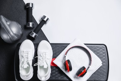 Photo of Different gym stuff and headphones on white background, flat lay. Space for text