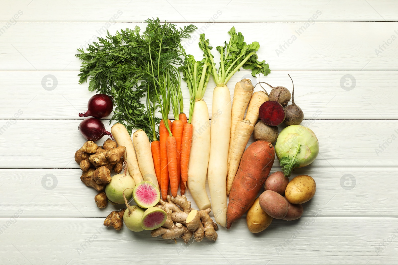 Photo of Different root vegetables on white wooden table, flat lay