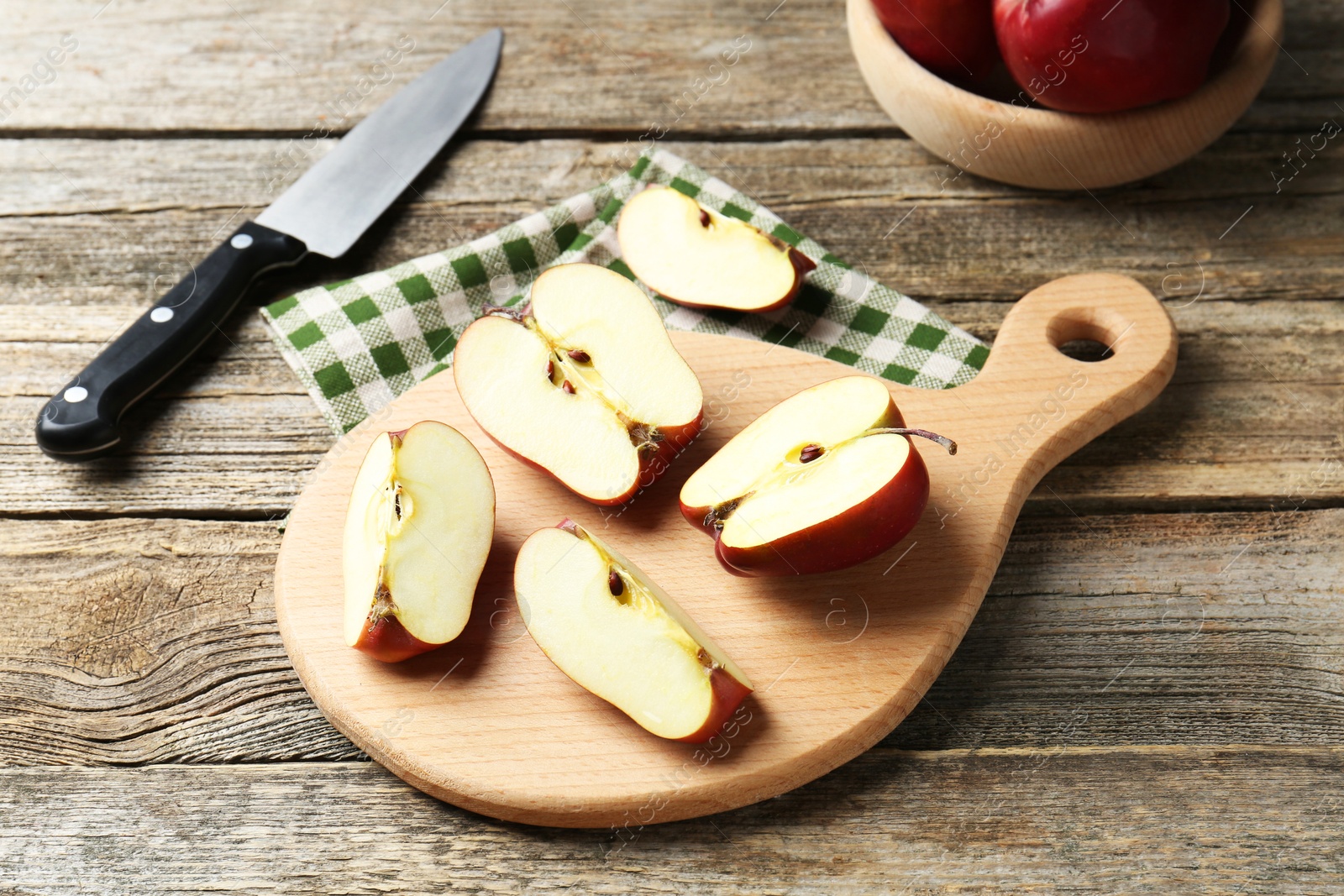 Photo of Cutting board, cut apples and knife on wooden table