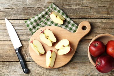 Photo of Cutting board, cut apples and knife on wooden table, flat lay