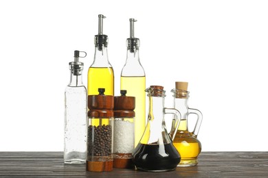 Photo of Salad dressings and spices on wooden table against white background