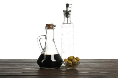 Photo of Salad dressings and olives on wooden table against white background