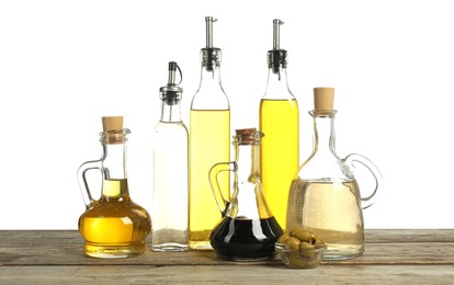 Photo of Salad dressings and olives on wooden table against white background