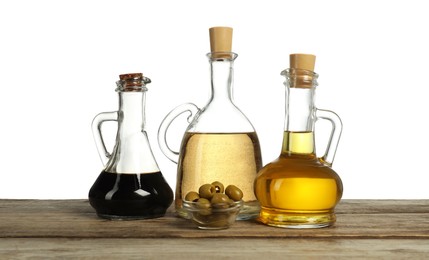 Photo of Salad dressings and olives on wooden table against white background