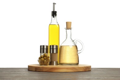 Photo of Salad dressings, spices and olives on wooden table against white background