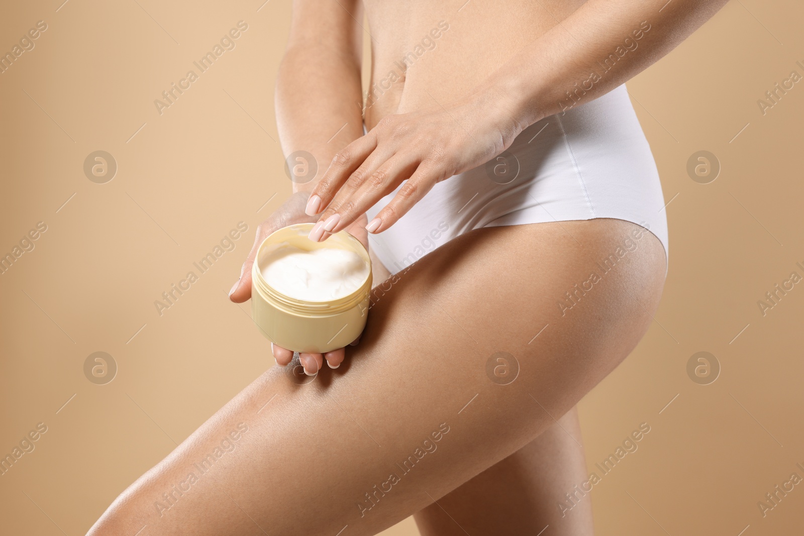 Photo of Woman applying anti cellulite cream on beige background, closeup