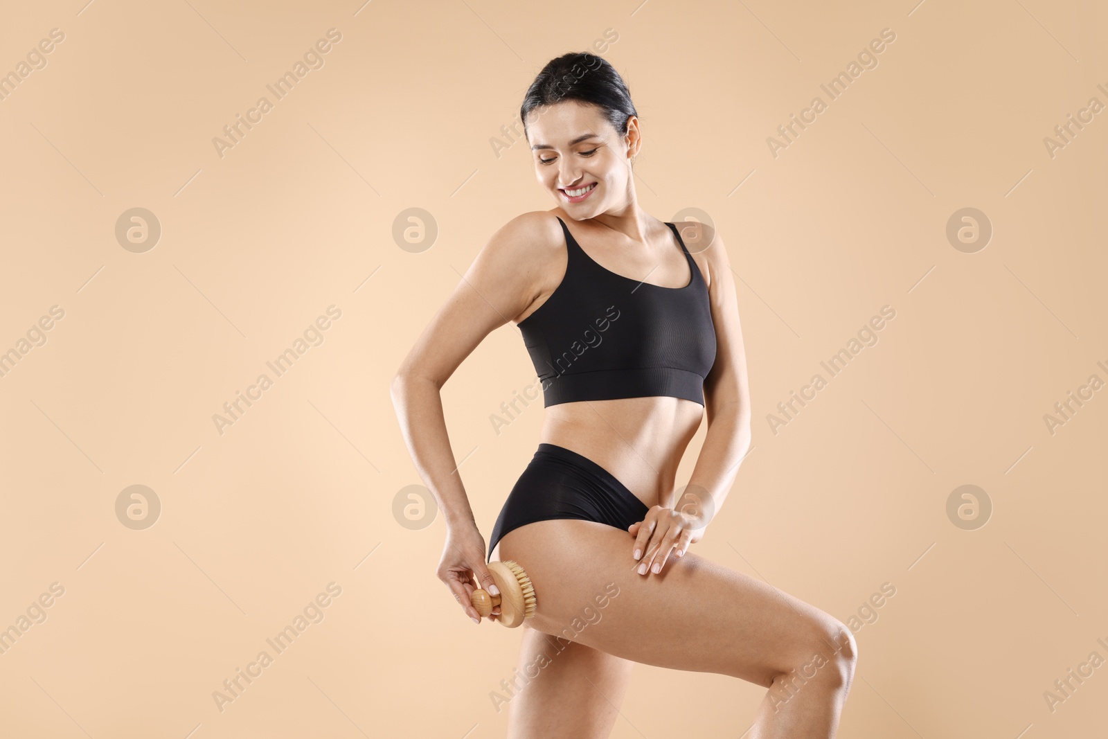 Photo of Woman doing anti cellulite massage with brush on beige background