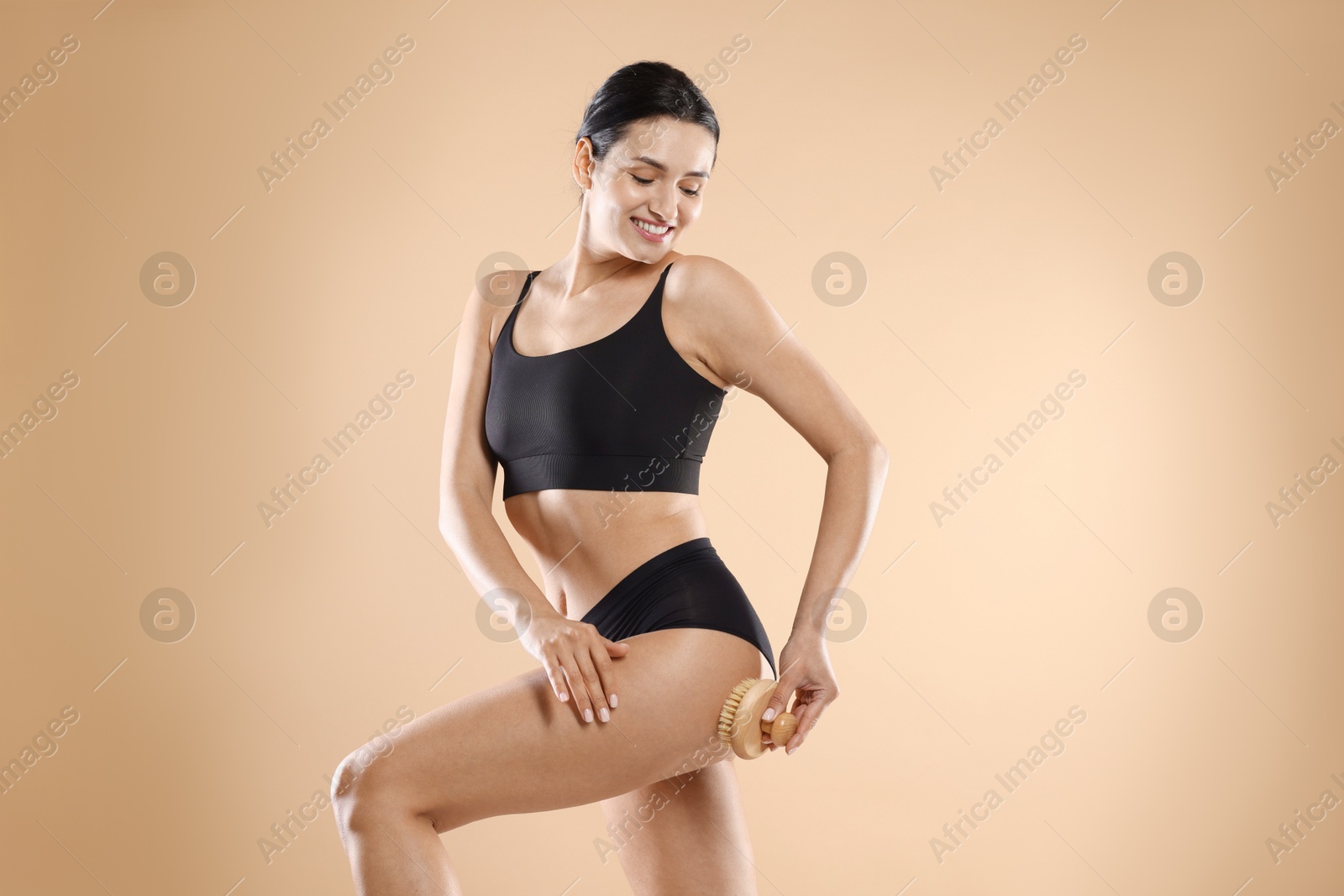 Photo of Woman doing anti cellulite massage with brush on beige background