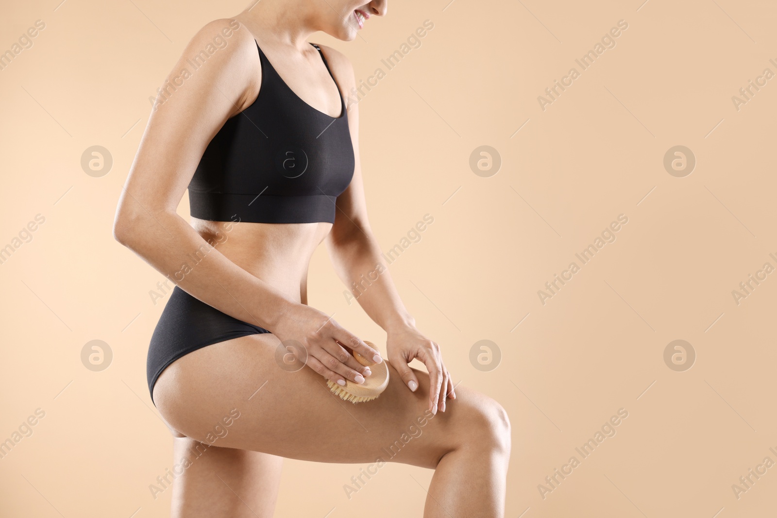 Photo of Woman doing anti cellulite massage with brush on beige background, closeup. Space for text