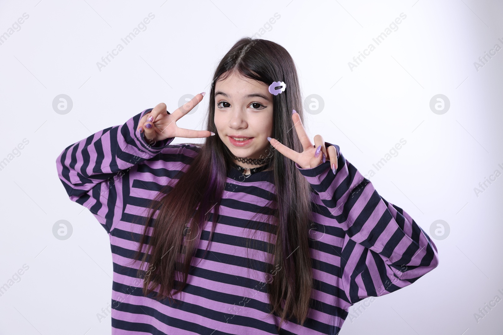 Photo of Teenage girl in stylish clothes and accessories showing V-sign on white background. Makeup in anime style