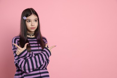 Photo of Teenage girl in stylish clothes and accessories posing on pink background, space for text. Makeup in anime style