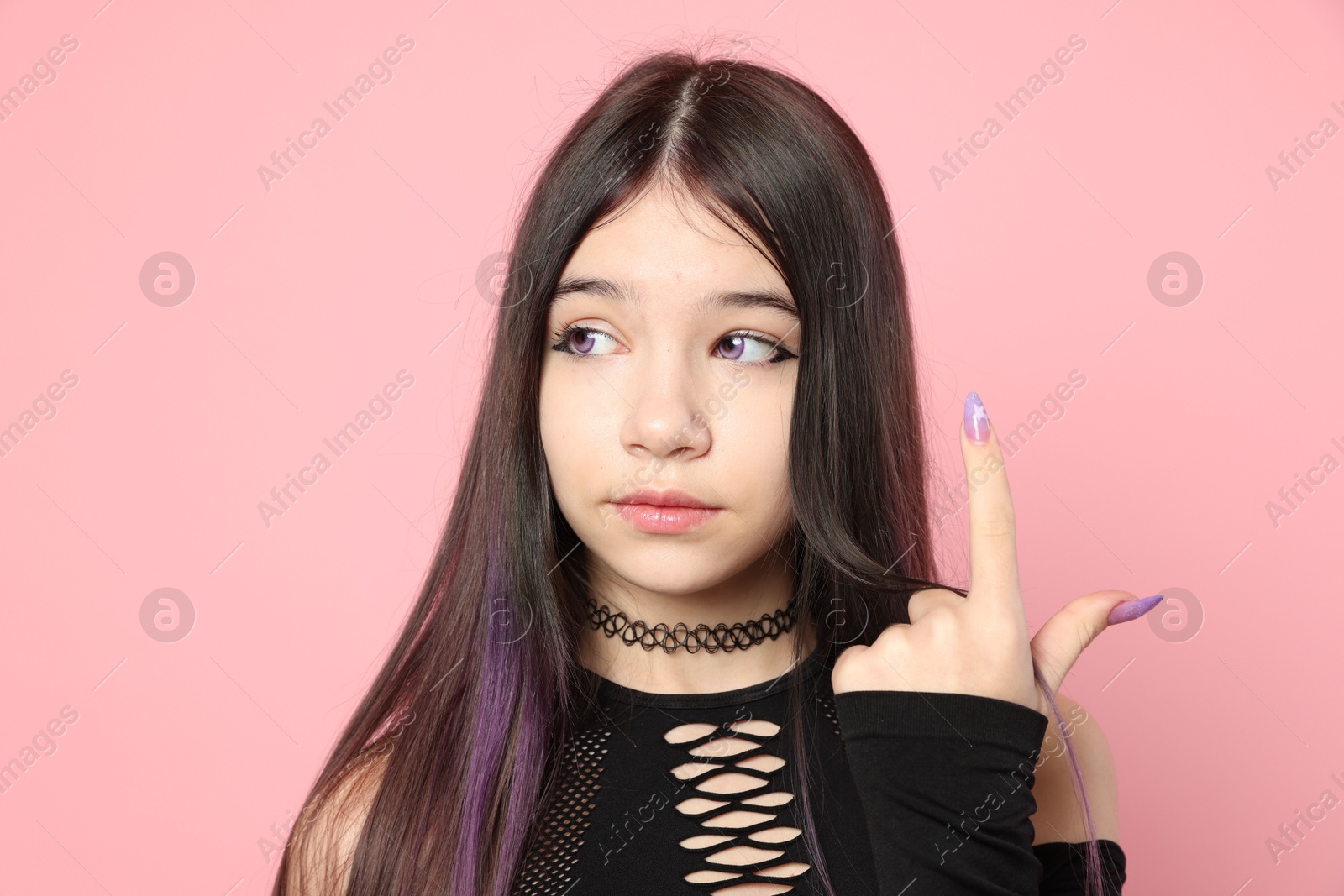 Photo of Teenage girl posing on pink background. Makeup and clothes in anime style