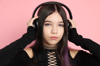 Photo of Teenage girl with headphones posing on pink background. Makeup and clothes in anime style