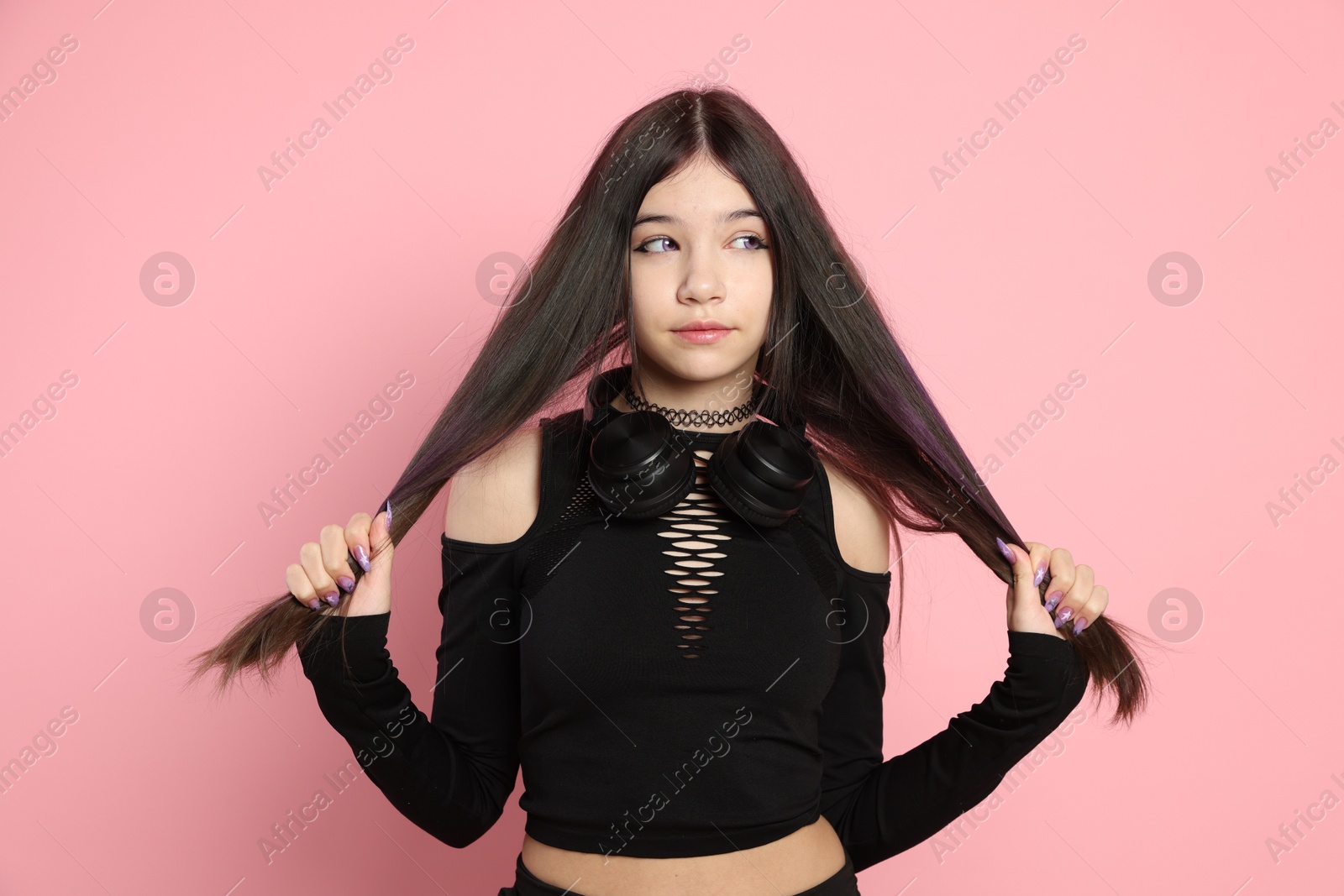 Photo of Teenage girl with headphones posing on pink background. Makeup and clothes in anime style