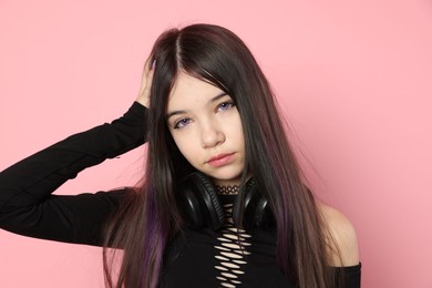 Teenage girl with headphones posing on pink background. Makeup and clothes in anime style