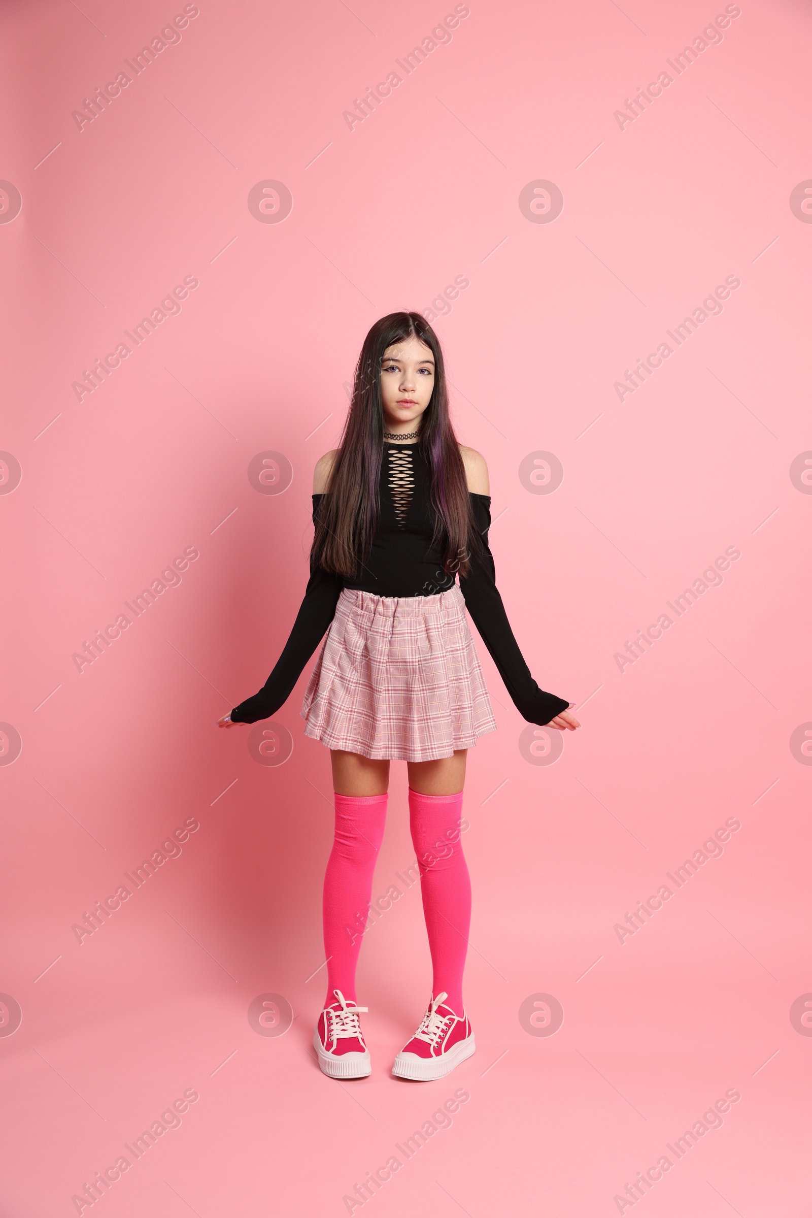 Photo of Teenage girl posing on pink background. Makeup and clothes in anime style