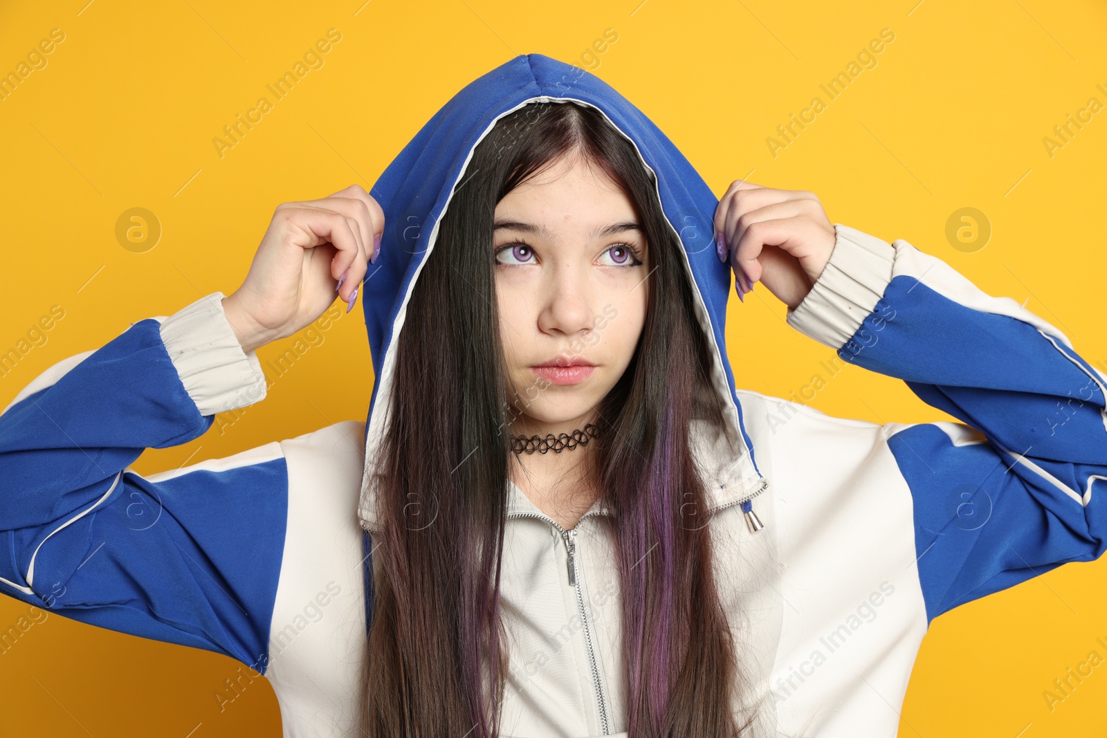 Photo of Teenage girl in stylish clothes posing on orange background. Makeup in anime style