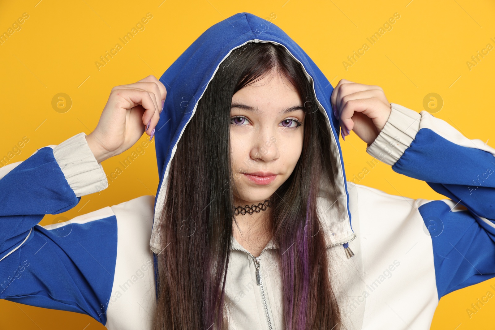 Photo of Teenage girl in stylish clothes posing on orange background. Makeup in anime style