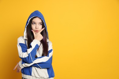 Photo of Teenage girl in stylish clothes posing on orange background, space for text. Makeup in anime style