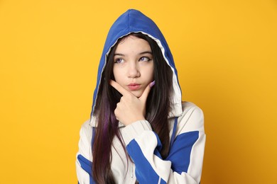 Photo of Teenage girl in stylish clothes posing on orange background. Makeup in anime style