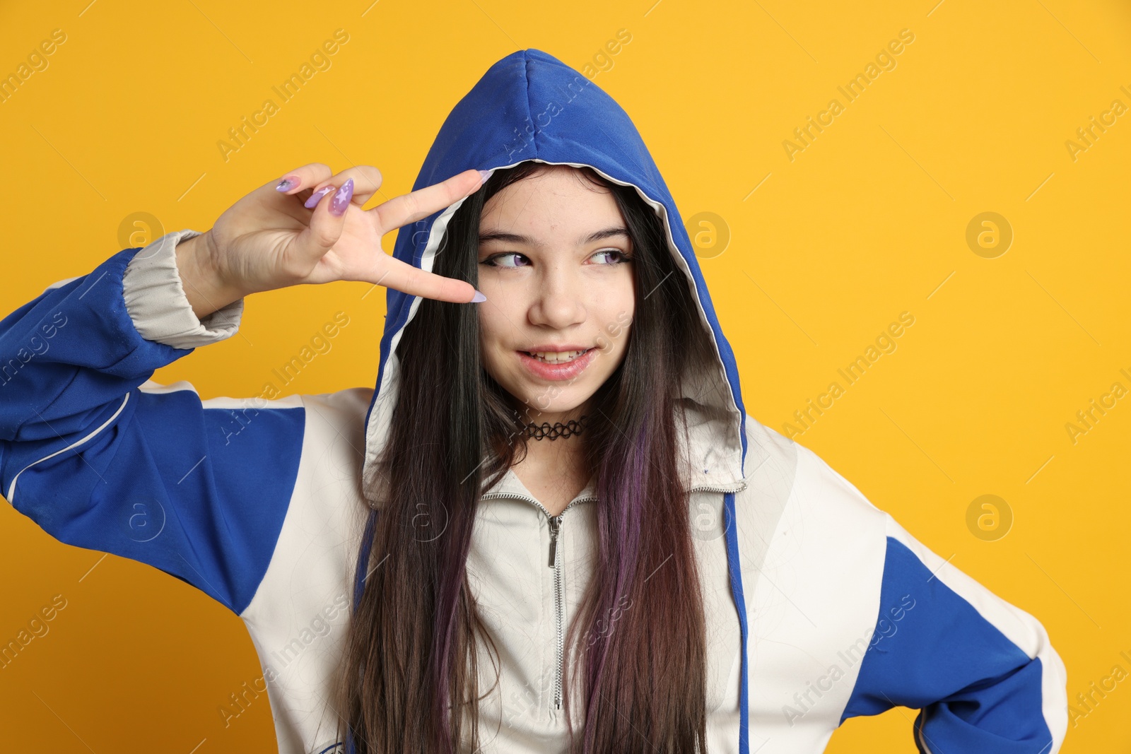 Photo of Teenage girl in stylish clothes posing on orange background. Makeup in anime style