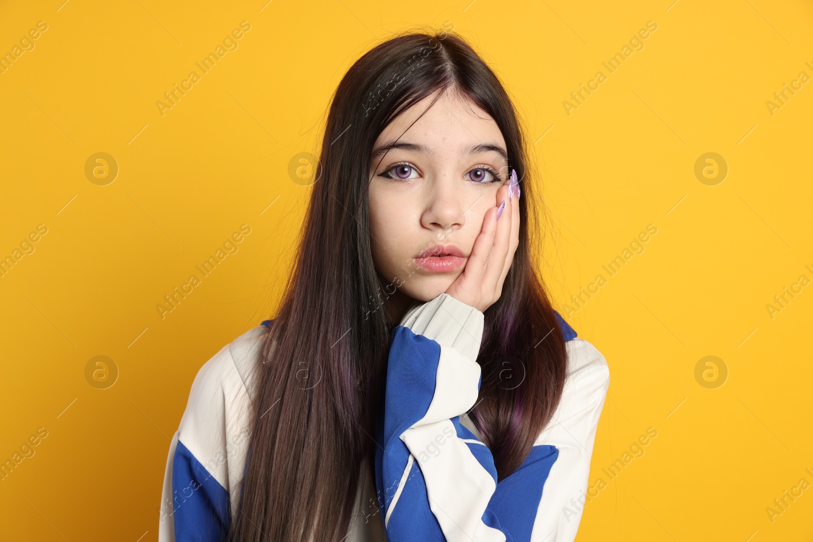 Photo of Teenage girl in stylish clothes posing on orange background. Makeup in anime style