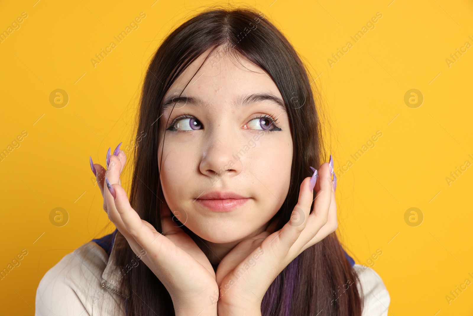 Photo of Teenage girl in stylish clothes posing on orange background. Makeup in anime style