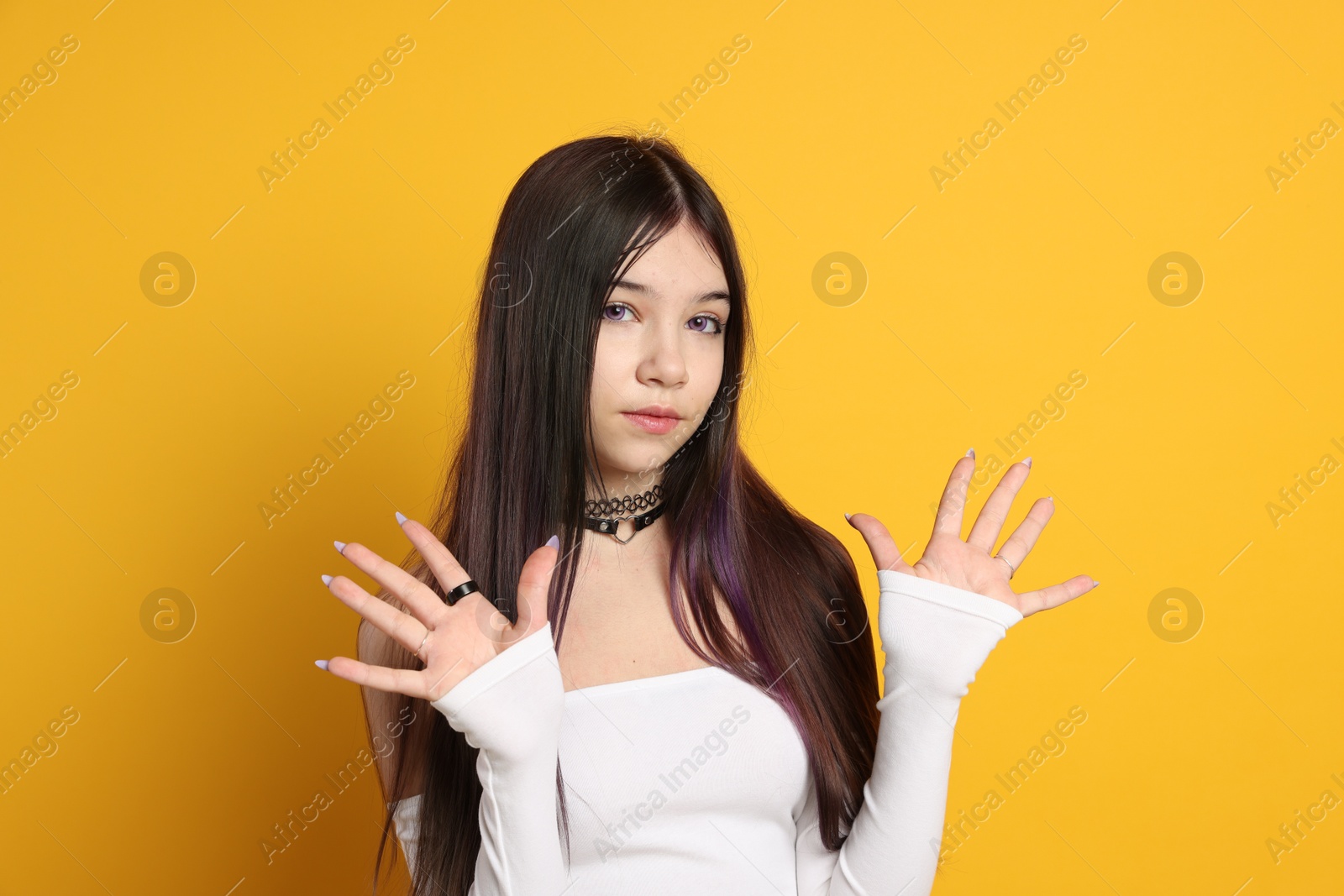 Photo of Teenage girl wearing stylish clothes and accessories on orange background. Makeup in anime style