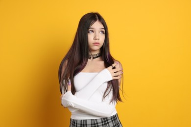 Teenage girl wearing stylish clothes and accessories on orange background. Makeup in anime style