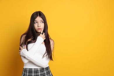 Teenage girl wearing stylish clothes and accessories on orange background, space for text. Makeup in anime style