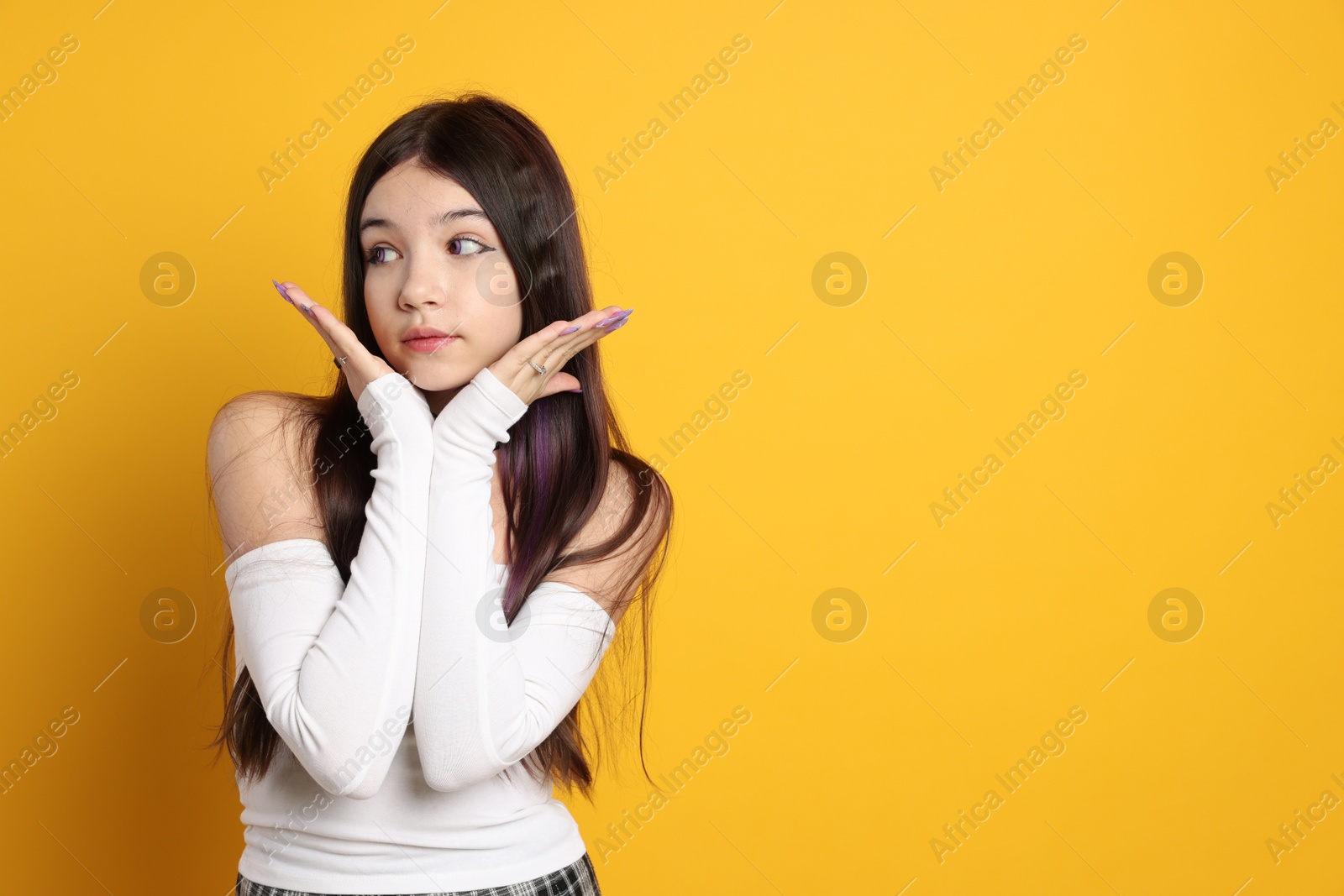 Photo of Teenage girl wearing stylish clothes and accessories on orange background, space for text. Makeup in anime style