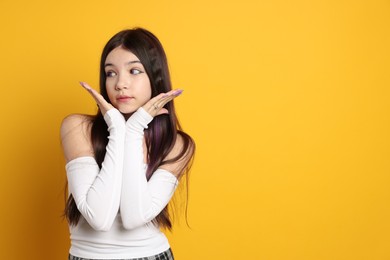 Photo of Teenage girl wearing stylish clothes and accessories on orange background, space for text. Makeup in anime style